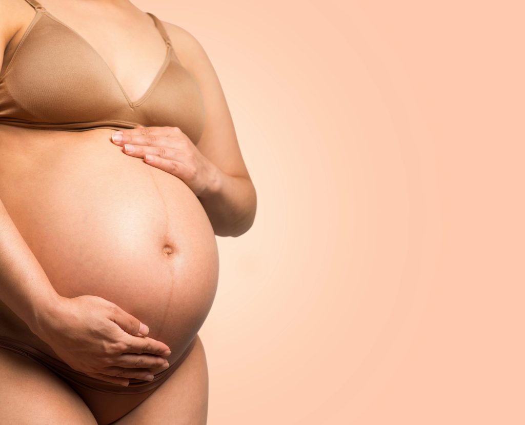 A pregnant woman gently cradles her belly, symbolizing motherhood and love.